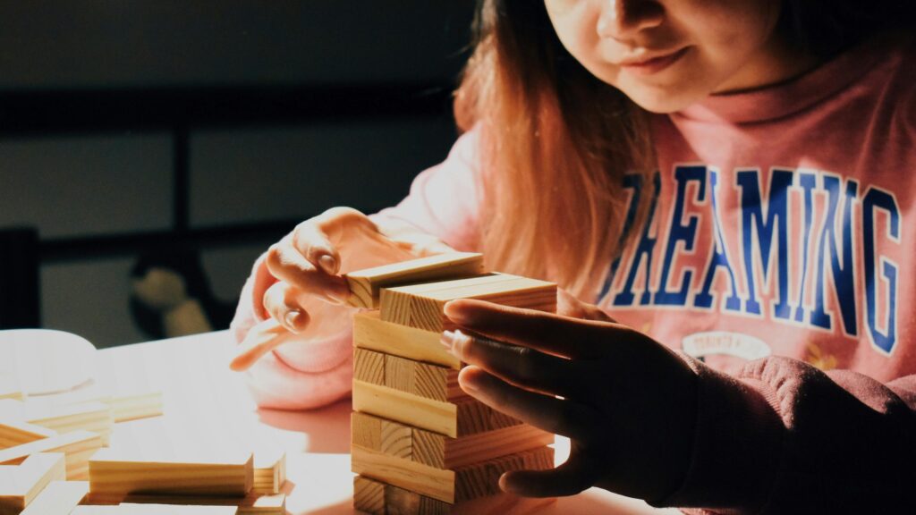 Person Concentrating on Jenga Tower Game PC Wallpaper