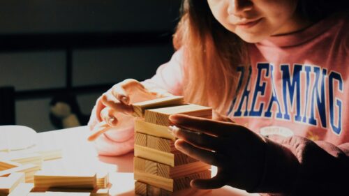Person Concentrating on Jenga Tower Game PC Wallpaper