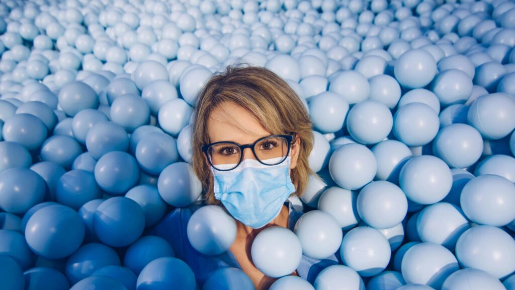 Person Wearing Face Mask in Blue Ball Pit High Resolution 4K Desktop Wallpaper