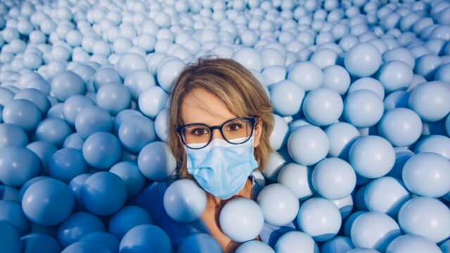 Person Wearing Face Mask in Blue Ball Pit High Resolution 4K Desktop Wallpaper