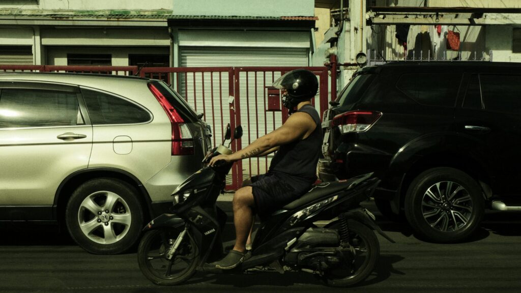 Man Riding Scooter Between Cars Urban Street 4K Wallpaper