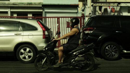 Man Riding Scooter Between Cars Urban Street 4K Wallpaper