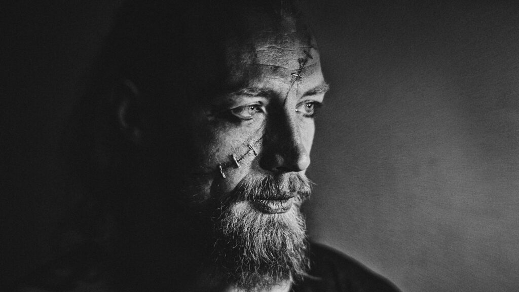 Dramatic Portrait of a Scarred Warrior in Black and White 4K Wallpaper