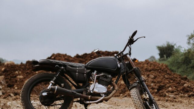 Custom Black Scrambler Motorcycle on Off-road Terrain 4K Wallpaper