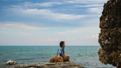 Woman Meditating on Coastal Rock with Dog at Seaside 4K Desktop Wallpaper