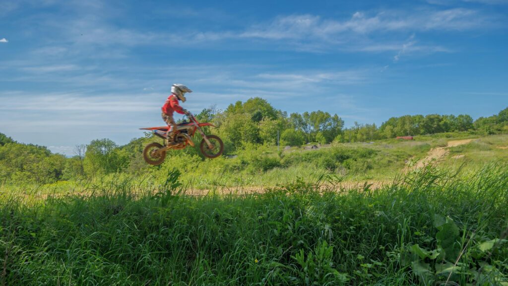 Dirt Bike Rider Jumping in Sunny Countryside 4K Wallpaper