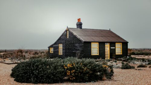 Black Cottage with Yellow Windows at Dungeness 4K Desktop Wallpaper
