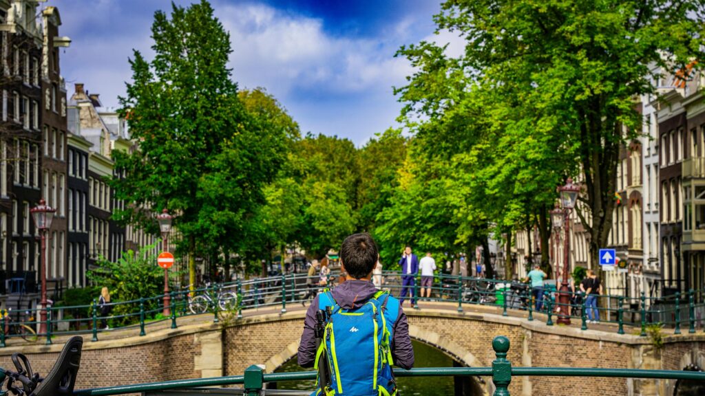 Traveler Admiring Amsterdam Canal View 4K Desktop Wallpaper