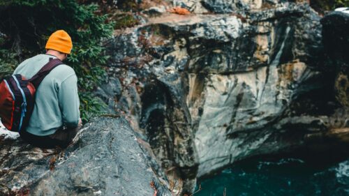 Hiker Sitting on Canyon Cliff Overlooking Blue River Desktop Wallpaper