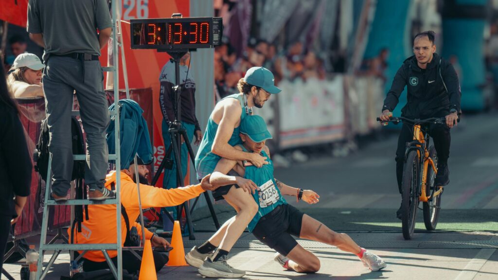 Exhausted Runner Being Supported at Marathon Finish Line 4K Wallpaper