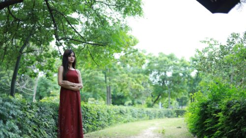 Beautiful Woman in Red Dress Standing in Lush Green Garden Desktop Wallpaper