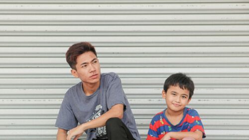 Young Brothers Sitting Together Before Metal Garage Door Desktop Wallpaper