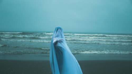 Ghostly Figure in Blue Veil at Sea Shore 4K Desktop Wallpaper