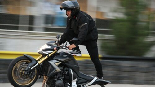 Stunt Rider Performing Wheelie on Honda Motorcycle 4K Wallpaper