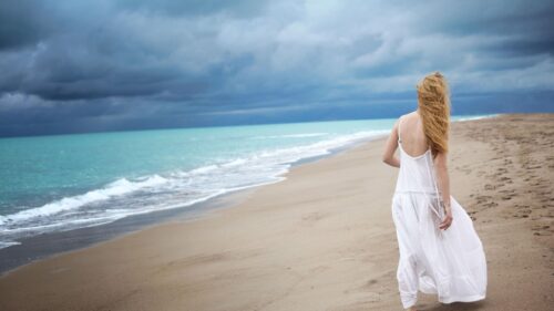 Blonde Woman in White Dress Walking on Stormy Beach Desktop Wallpaper