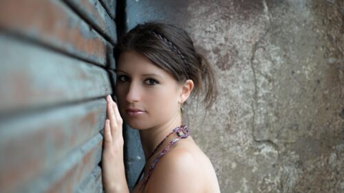 Beautiful Young Woman Leaning Against Rustic Metal Wall Desktop Wallpaper