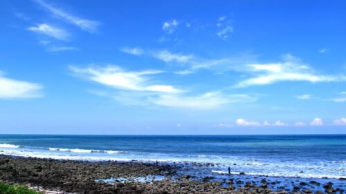 Serene Rocky Beach Coastline with Clear Blue Sky Desktop Wallpaper