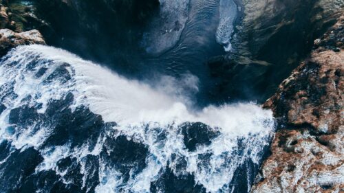 Stunning Aerial View of Icelandic Waterfall Cascading Over Rugged Cliffs 4K Wallpaper