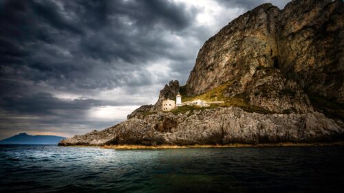 Dramatic Coastal Lighthouse Under Stormy Clouds Desktop Wallpaper
