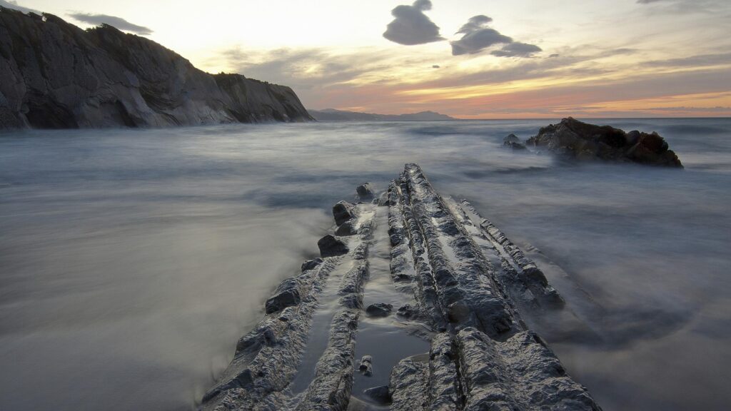 Dramatic Coastal Sunset with Jagged Rock Formations Desktop Wallpaper