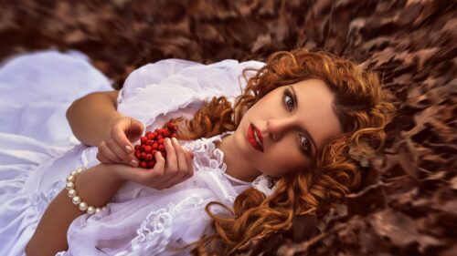 Beautiful Redhead Woman Holding Rowan Berries on Autumn Leaves 4K Desktop Wallpaper