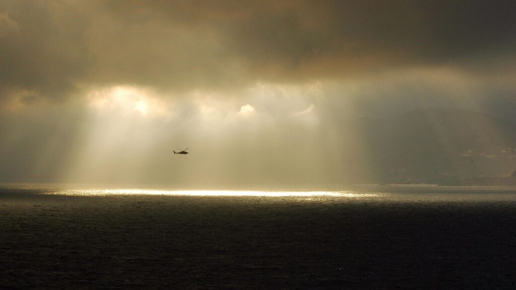 Helicopter Flying Through Dramatic Storm Clouds Over The Ocean Desktop Wallpaper
