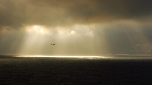 Helicopter Flying Through Dramatic Storm Clouds Over The Ocean Desktop Wallpaper