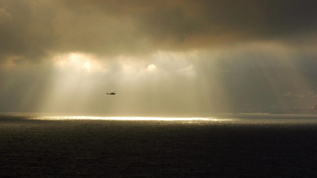 Helicopter Flying Through Dramatic Storm Clouds Over The Ocean Desktop Wallpaper