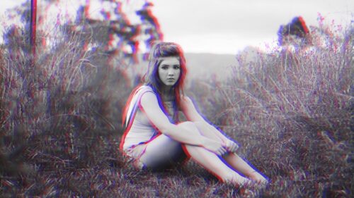Glitch Art Portrait of a Young Woman Sitting in a Grassy Field 4K Wallpaper