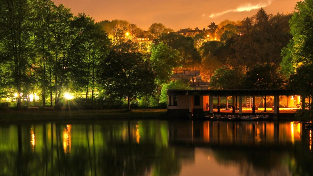 Serene Lakeside Park at Night with Golden Glow and Reflections Desktop Wallpaper