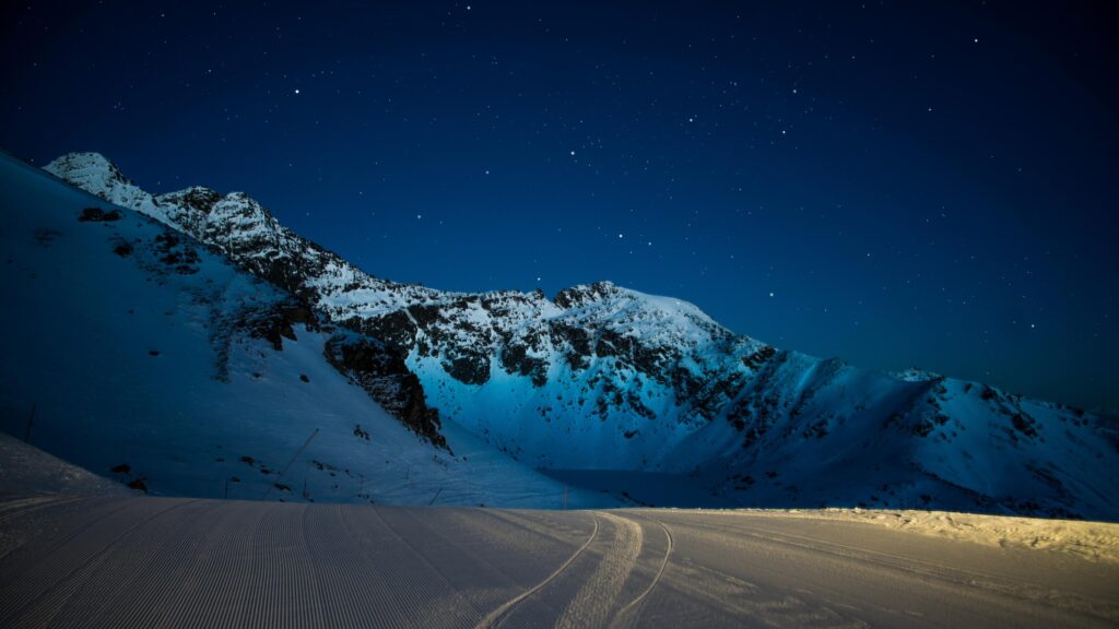 Breathtaking Snowy Mountain Peaks Under Starry Night Sky 4K Desktop Wallpaper