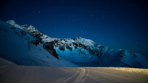 Breathtaking Snowy Mountain Peaks Under Starry Night Sky 4K Desktop Wallpaper