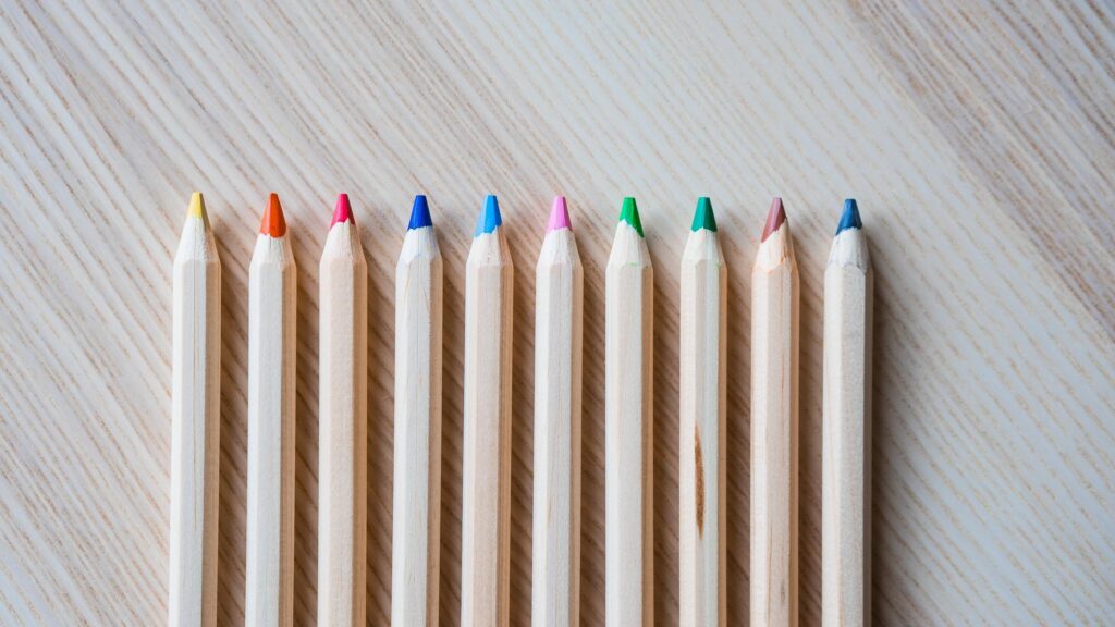Minimalist Row of Colorful Wooden Pencils on Light Textured Surface 4K Wallpaper