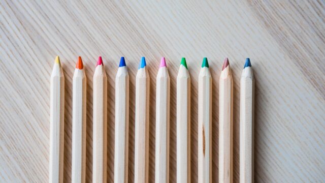 Minimalist Row of Colorful Wooden Pencils on Light Textured Surface 4K Wallpaper