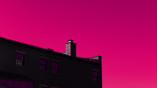 Minimalist Brick Building Silhouette Against a Vibrant Pink Sunset 4K Desktop Wallpaper