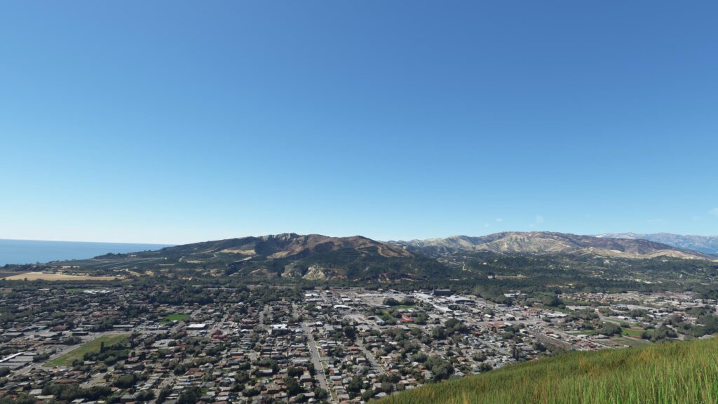 Panoramic Aerial View of Coastal Town nestled by Hills Desktop Wallpaper