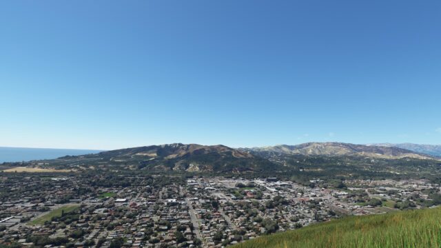 Panoramic Aerial View of Coastal Town nestled by Hills Desktop Wallpaper