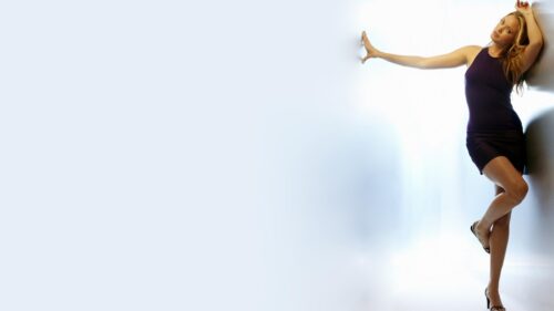 Beautiful Blonde Woman in Elegant Purple Dress Posing Against White Wall 4K Wallpaper
