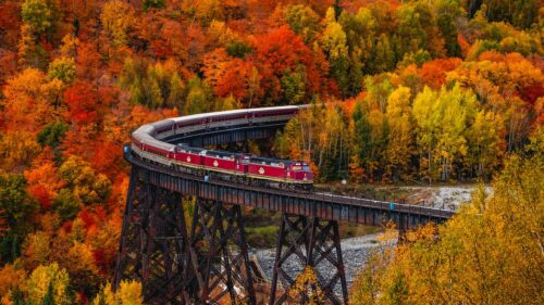 Stunning Maroon Train Crossing a Trestle Bridge in Autumn Foliage 4K Wallpaper