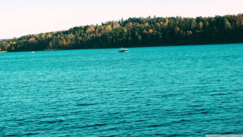 Boats Cruising on a Serene Blue Lake with Autumn Forest Backdrop 4K Wallpaper