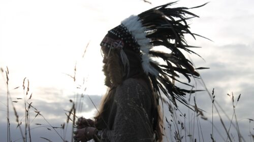 A Person Wearing a Traditional Feather Headdress in a Golden Meadow Desktop Wallpaper