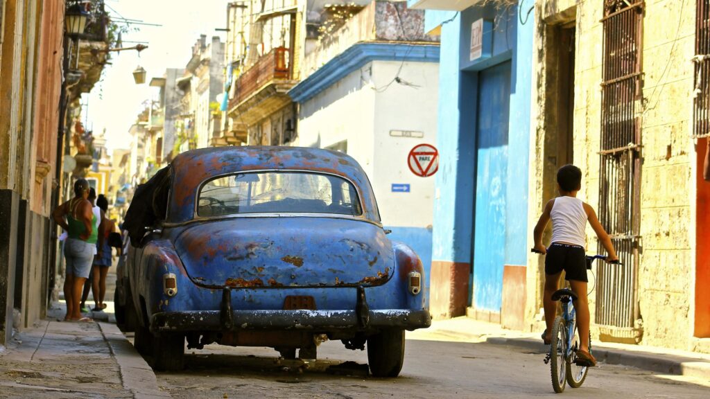 Vintage Blue Car and Child Cycling on Havana Street Desktop Wallpaper