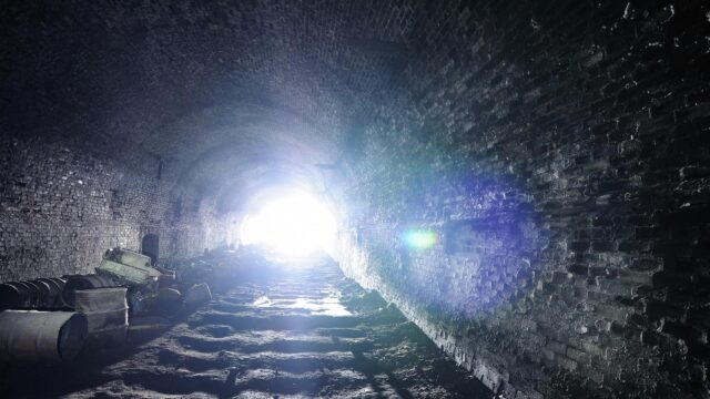 Mysterious Abandoned Tunnel with Glowing Exit Light 4K Wallpaper