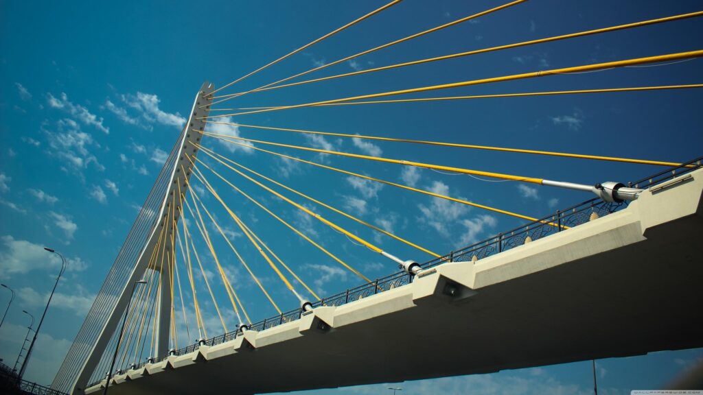 Stunning Yellow Suspension Bridge Cables Against a Vibrant Blue Sky Desktop Wallpaper