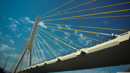 Stunning Yellow Suspension Bridge Cables Against a Vibrant Blue Sky Desktop Wallpaper