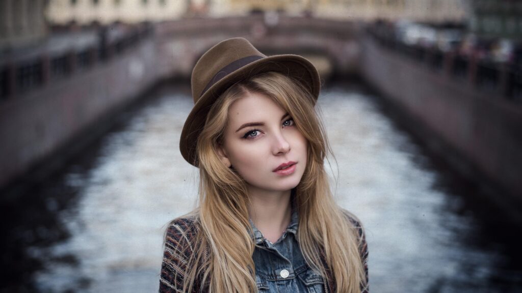 Stunning Blonde Woman Wearing a Fedora Hat by a City Canal Desktop Wallpaper