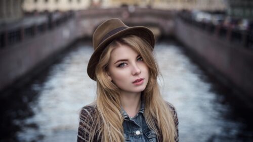Stunning Blonde Woman Wearing a Fedora Hat by a City Canal Desktop Wallpaper