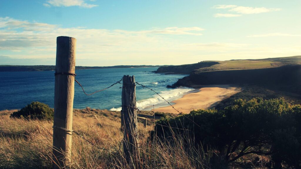 Coastal Fence overlooking Sandy Beach and Ocean Horizon Desktop Wallpaper