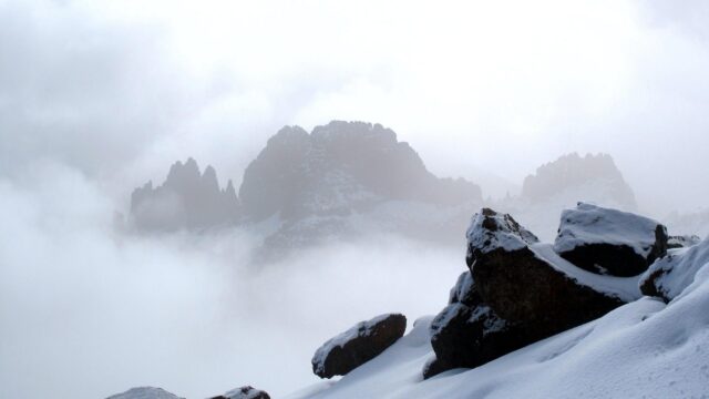 Misty Mountain Peaks Amidst Snow and Clouds Desktop Wallpaper