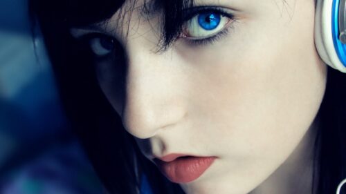Stunning Close-Up Portrait of a Girl with Bright Blue Eyes and Headphones 4K Desktop Wallpaper